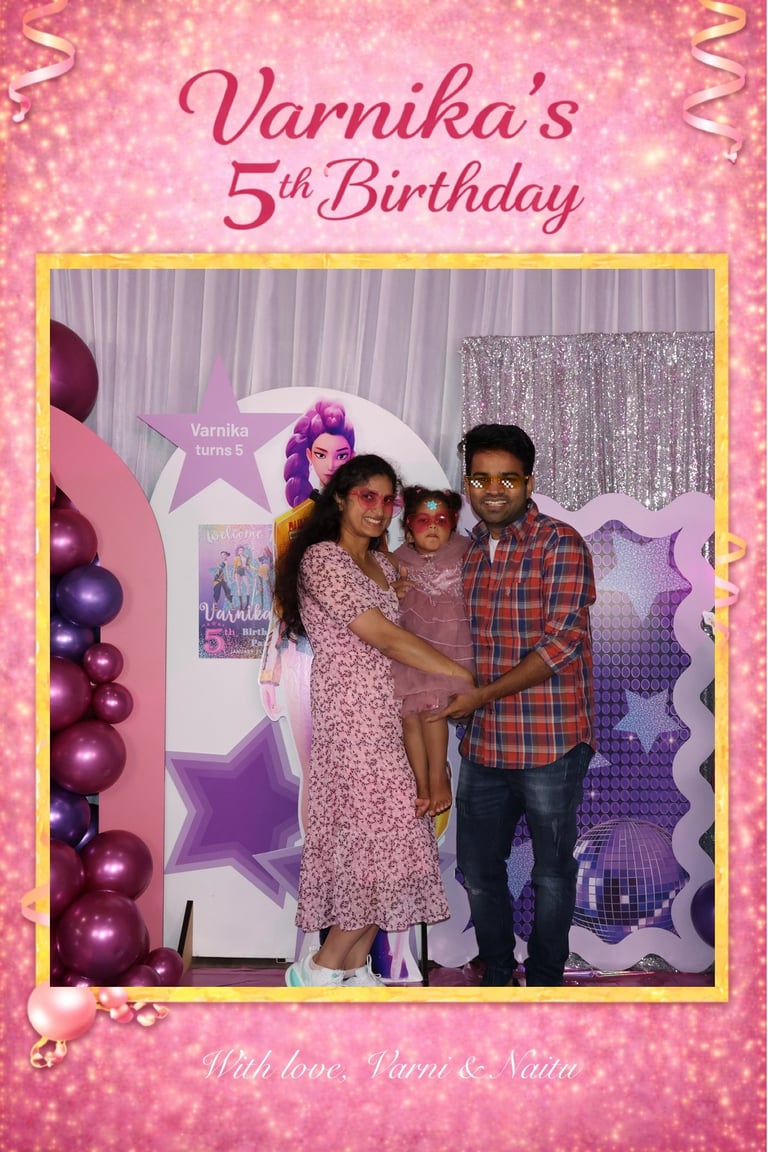 Family photo at Varnikas 5th birthday celebration with pink and purple decorations, balloons, and backdrop